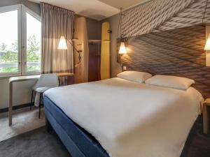 a hotel room with a large bed and a window at ibis Orleans Centre Gare in Orléans