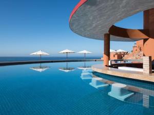 a swimming pool with umbrellas and the ocean at Club Regina Los Cabos in San José del Cabo