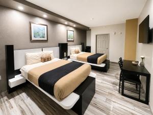 two beds in a hotel room with a desk and a bed at Crystal Inn Downtown in Houston