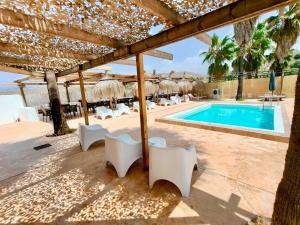 a resort with a swimming pool and white chairs at Fuente del Lobo Glamping & Bungalows - Adults Only in Pinos Genil