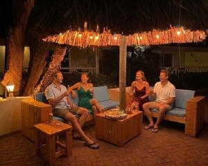 a group of people sitting on a couch under an umbrella at Blue Marlin Apartments, nabij Mambo Beach in Willemstad