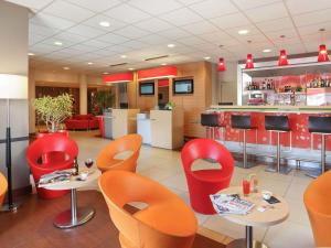 a restaurant with red chairs and tables and a bar at Ibis Le Havre Sud Harfleur in Harfleur