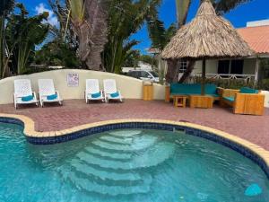 a swimming pool with four chairs and a table at Blue Marlin Apartments, nabij Mambo Beach in Willemstad