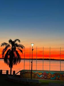 a palm tree and a street light with a sunset at Cabaña Doña Adela II in Paso de la Patria