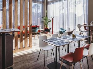 a restaurant with tables and chairs and large windows at ibis Mulhouse Centre Filature in Mulhouse