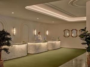 a woman standing at a table in a lobby at The Brighton Hotel Sydney - Mgallery Collection in Sydney