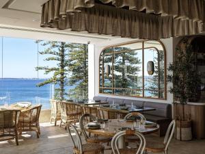 a restaurant with tables and chairs and a large window at The Brighton Hotel Sydney - Mgallery Collection in Sydney