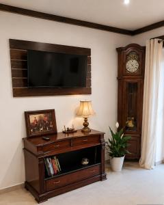 a living room with a tv on the wall and a clock at Pokój dyrektora stadniny in Niezgoda