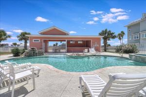 a swimming pool with white chairs and a house at Port A Del Rey in Port Aransas