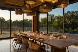 a long wooden table in a room with windows at Garrya Bianti Yogyakarta in Yogyakarta