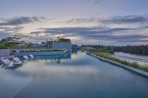 a swimming pool with chairs and a river at Mandai Rainforest Resort by Banyan Tree in Singapore