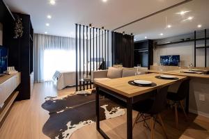 a kitchen and living room with a wooden table and a dining room at Loft 406 Inn - Parque Una + garagem in Pelotas