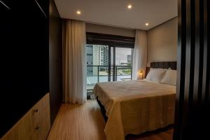 a bedroom with a bed and a large window at Loft 406 Inn - Parque Una + garagem in Pelotas