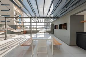 a large room with a white table and benches at Loft 406 Inn - Parque Una + garagem in Pelotas