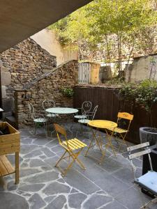 a patio with tables and chairs and a stone wall at Auberge des Veillees in Blesle