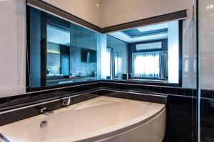 武里南Cresco Hotel Buriram的带窗户的浴室里有一个大浴缸