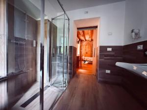 a glass shower in a bathroom with a wooden floor at Locanda Ponte Serra in Lamon