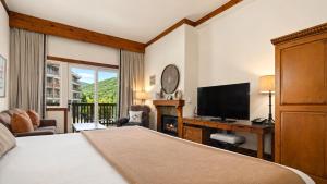 a bedroom with a bed and a desk with a television at 147 Studio Spruce Peak Lodge at Stowe Mt Resort Sleeps 4 in Stowe