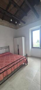a bedroom with a bed with a red comforter and a window at Dimora del Cammino di Cancellara in Foligno