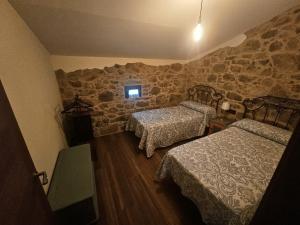a bedroom with two beds and a stone wall at El Lagar de Mailusa in Sayar