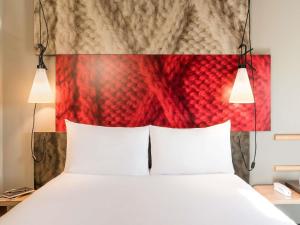 a bed with two white pillows and a red headboard at ibis Paris Saint-Denis Stade Sud in Saint-Denis