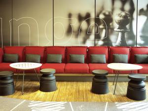 a red couch with two tables and two stools at ibis Paris Saint-Denis Stade Sud in Saint-Denis