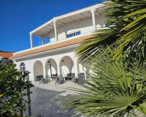 a large white building with arches and a palm tree at Villa Anny Fronte Mare in Avola