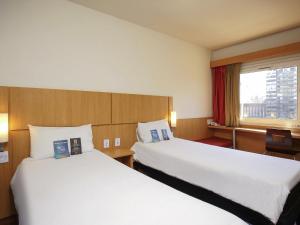 a hotel room with two beds and a window at ibis Buenos Aires Congreso in Buenos Aires