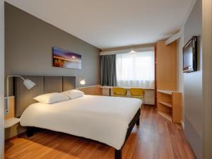 a hotel room with a large white bed and chairs at ibis Hotel Würzburg City in Würzburg