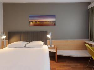 a hotel room with a bed and a desk and a tv at ibis Hotel Würzburg City in Würzburg