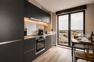a kitchen with black cabinets and a table and a window at City Penthouse - Roof Terrace & Free Parking in Beeston Hill