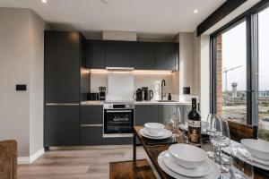 a kitchen with black cabinets and a table with wine glasses at City Penthouse - Roof Terrace & Free Parking in Beeston Hill