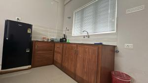 a kitchen with a black refrigerator and wooden cabinets at Stay near to temple 240m in Guruvāyūr