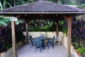 a wooden gazebo with a table and chairs at DOMAINE de VALCINE 3 gites parc et piscine à 4 mn de la distillerie DBM, des 1er commerces et de la cascade de BIS in Sainte-Rose