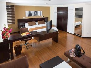 a bedroom with a bed and a desk with a computer at Mercure Alameda Quito in Quito