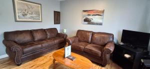 a living room with two brown leather couches and a table at The Moosehead in Glenwood