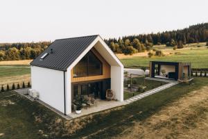 a small house with a black roof on a field at Projekt Babia - Domek z jacuzzi in Lipnica Wielka