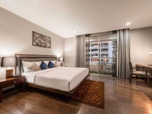 a bedroom with a bed and a table and a desk at Grand Mercure Bangkok Asoke Residence in Bangkok