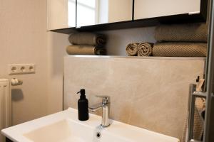 a bathroom sink with a bottle of soap on it at Fewo zum Ritzli in Ettenheim +19 photos