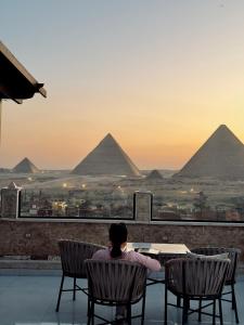 a person sitting at a table looking at the pyramids at Continental Pyramids INN & Roof Top in Cairo