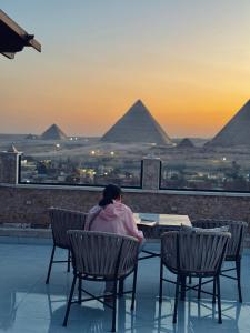 a man sitting at a table looking at the pyramids at Continental Pyramids INN & Roof Top in Cairo