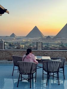 a person sitting in chairs looking out at the pyramids at Continental Pyramids INN & Roof Top in Cairo