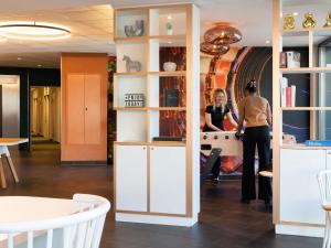 a woman is standing in a room with shelves at ibis budget Genève Petit-Lancy in Geneva