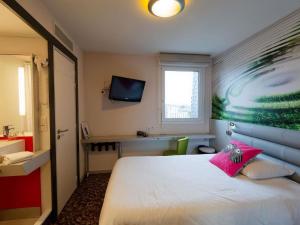 a bedroom with a white bed with a pink pillow at ibis Styles Saint Brieuc Gare Centre in Saint-Brieuc