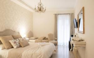 a white bedroom with a bed and a chandelier at PALAZZO ALESSANDRINI GUEST HOUSE in Viterbo