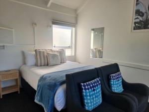 a bedroom with a bed and a couch and a window at Ohope Beach Motel in Ohope Beach