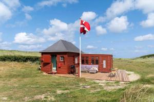 a small cabin with a flag on a deck at 1355-Vestervig-Klitvej-4 in Agger