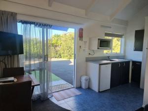 a kitchen with a sliding glass door leading to a yard at Ohope Beach Motel in Ohope Beach