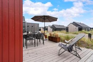 a deck with a table and chairs and an umbrella at 9954-Hvide-Sande-Langsand-214 in Hvide Sande