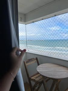 a person looking out a window at the beach at Apartamento Beira Mar in Maceió